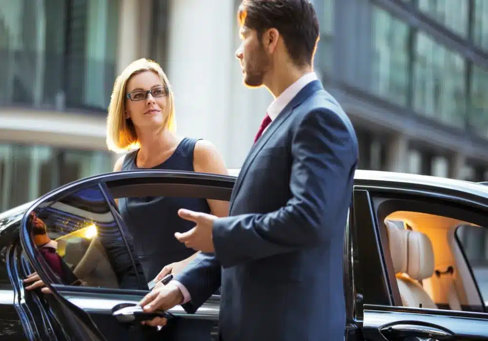 Home 6 Professioneller Chauffeur öffnet einer Dame die Tür einer Luxuslimousine vor einem Hotel in Zürich – exklusiver Limousinenservice Schweiz